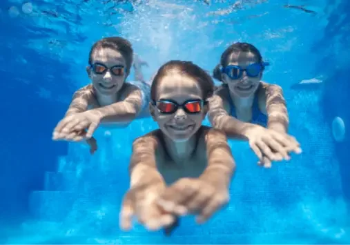 Children swimming underwater wearing goggles.