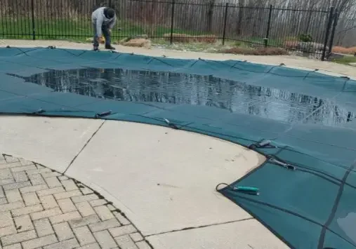 Person securing pool cover with tools.